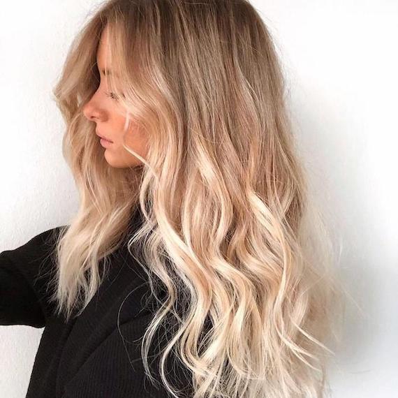 Side profile of woman with long, wavy, blonde hair and highlights, created using Wella Professionals