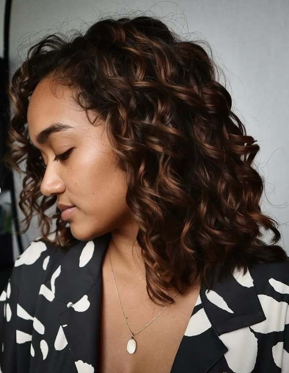 Defined natural curls with warm golden-caramel highlights, styled at Hera Hair Beauty, Singapore